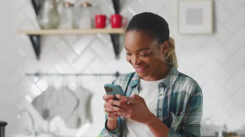 Smiling Woman Using Smartphone in Modern Kitchen