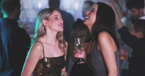 Two Women Laughing Together at a Crowded Party