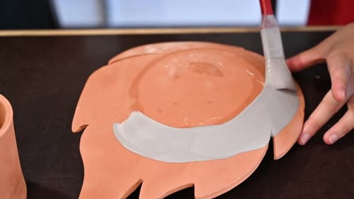 Woman painting a flower vase at pottery workshop