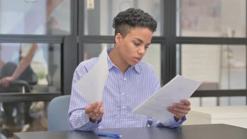 Mixed Race Woman Reading Documents in Office