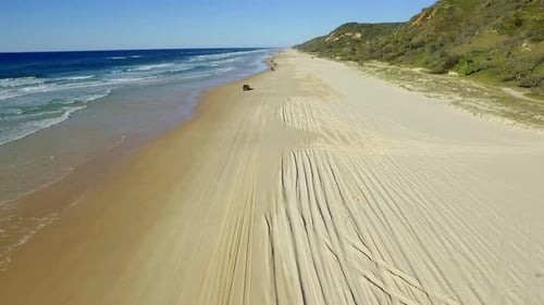 View along the broad golden sands of Fraser Island, with sharp shadows cast by the 4x4 tracks and a