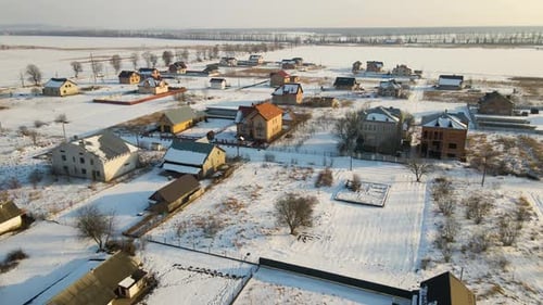 Aerial View of Private Homes with Snow Covered Roofs in Rural Suburbs Town Area in Cold Winter