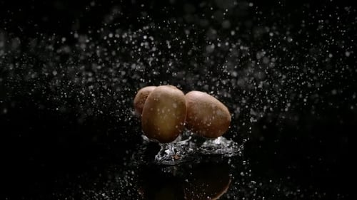 Three Kiwis Dropping and Splashing Water on Black