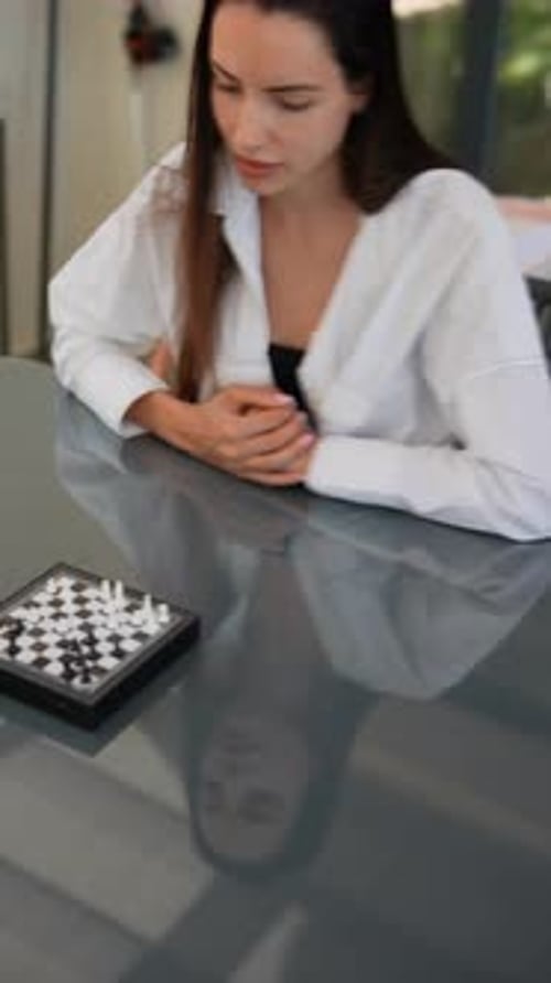 A Woman Immersed in Chess Tactics Displaying Focus and Strategic Thinking in a Modern Setting