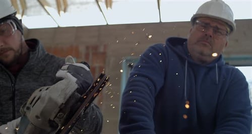 Construction Workers Use Grinder With Sparks at Workplace