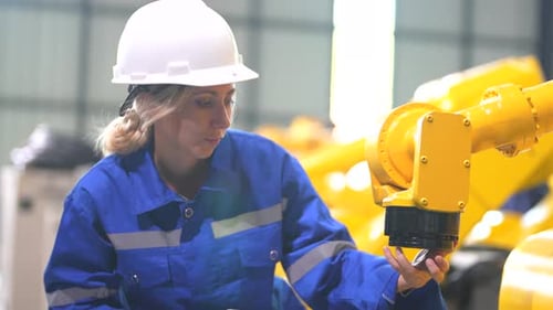 Female technician programs a robot arm with a digital tablet and assembly robot in a3105205454564623