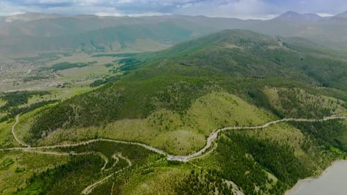 Camino sinuoso que rodea la colina cubierta de pinos. Imagen panorámica de hermosas montañas