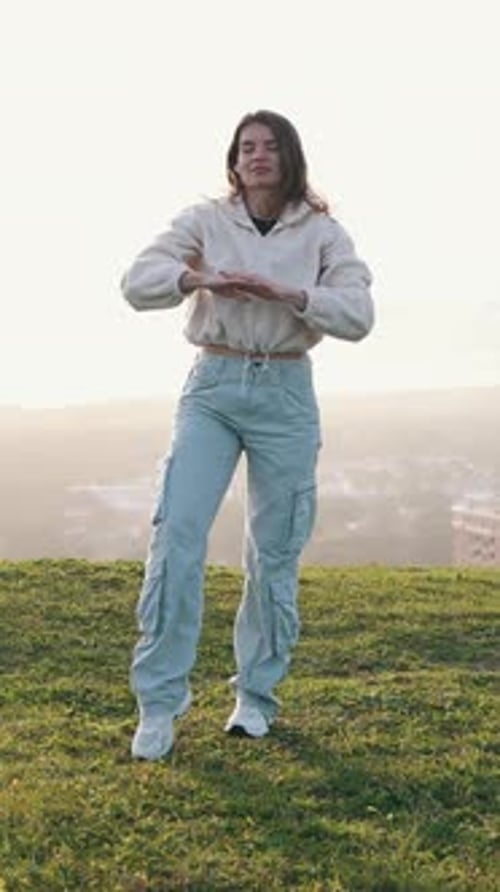 Young Woman Dancing on Grassy Hill in Daylight