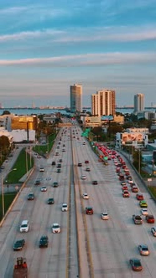 Lots of cars move by the multi-lane highway and stand in the congestion. Drone footage above Miami