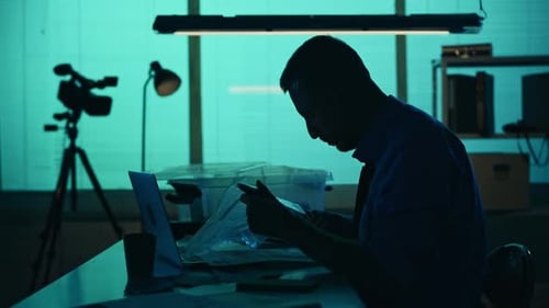 Man Examines Evidence in Dimly Lit Office
