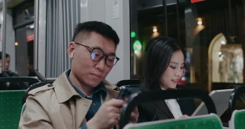 Man and Woman on Bus Using Technology