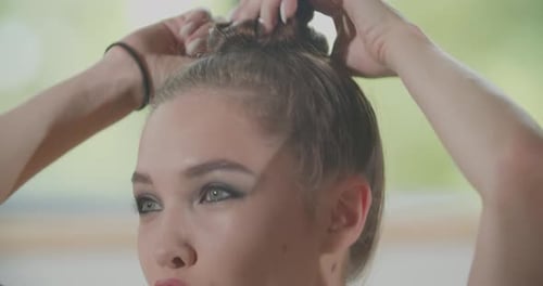 Woman Styles Hair Into Bun Close Up