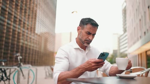 Mature businessman uses mobile phone sits on