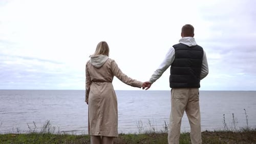 Couple Holding Hands Overlooking Ocean on Overcast Day