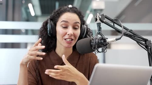 Cheerful woman recording podcast in studio with microphone