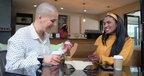 Diverses amies ouvrent une boîte, trouvent un bocal puis consultent leur smartphone pour examiner le contenu d'un café