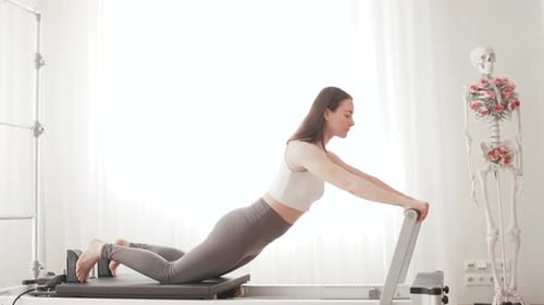 Woman Doing Pilates on Reformer Machine Indoors
