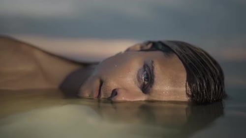 Person Floating in Water at Sunrise or Sunset