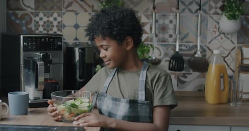 Young Boy Smiling with Fresh Salad in Kitchen