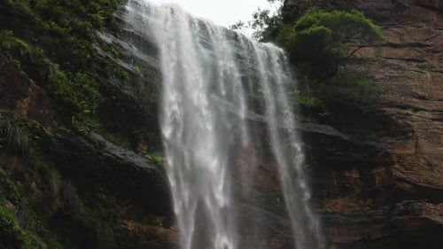 A Stunning Waterfall Cascades Down a Steep Cliff Into a Lush Forest Below Surrounded By Dense
