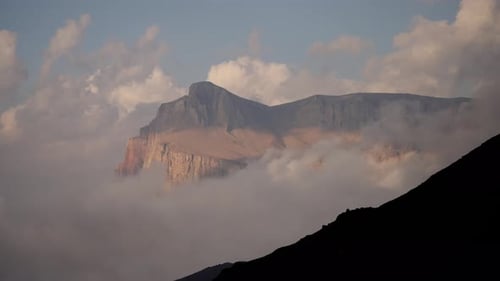 A Timelapse of a Huge Mountain Covered with Clouds Clouds Drift Around a Mountain Peak Partially