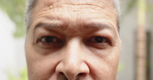 Close-up of person's face with neutral expression, focusing on features, at home