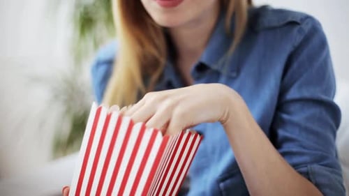 Blonde woman eating popcorn at home