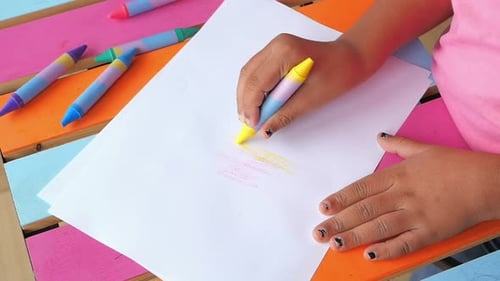 Child Drawing with Colorful Crayon on White Paper
