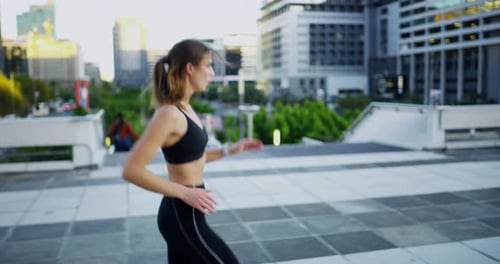4k video footage of an attractive young woman checking the time while out jogging in the city