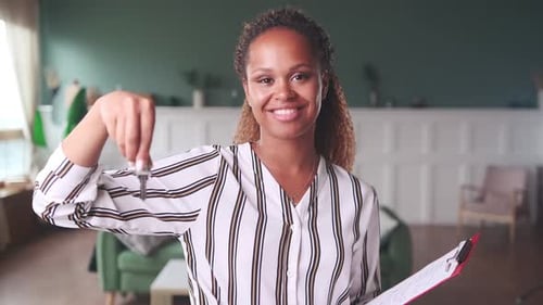 Woman Holding Key and Clipboard Smiling Indoors