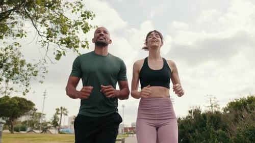 Young joyful active couple jogging together in the park on summer day, bottom-up view