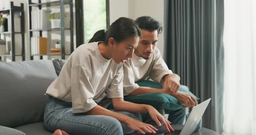 Young Couple Using Laptop Together on Couch at Home