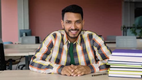 Smiling Man at Desk Gives Thumbs Up
