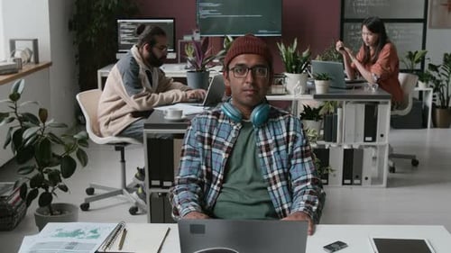 Portrait of Happy Indian Male Software Engineer with Headphones at Workplace