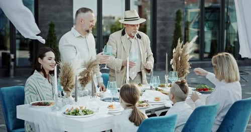 Happy Family Clinking Glasses During Banquet in Outdoor Restaurant