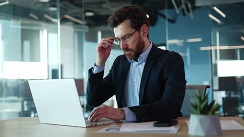 Caucasian Male Feeling Headache in Office While Working on Wireless Laptop