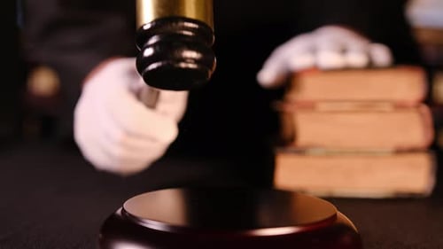 Close Up of Gavel Held By Judge Above Law Books Scene Represents Law Judgment and Justice