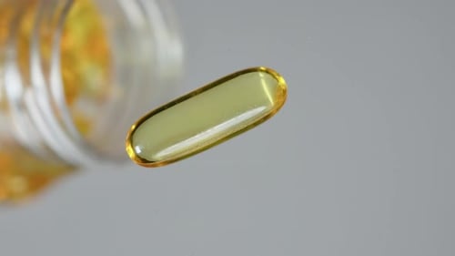 Close up macro pouring vitamine D3 capsules on flat surface. Omega 3 fish oil capsules. Natural medi