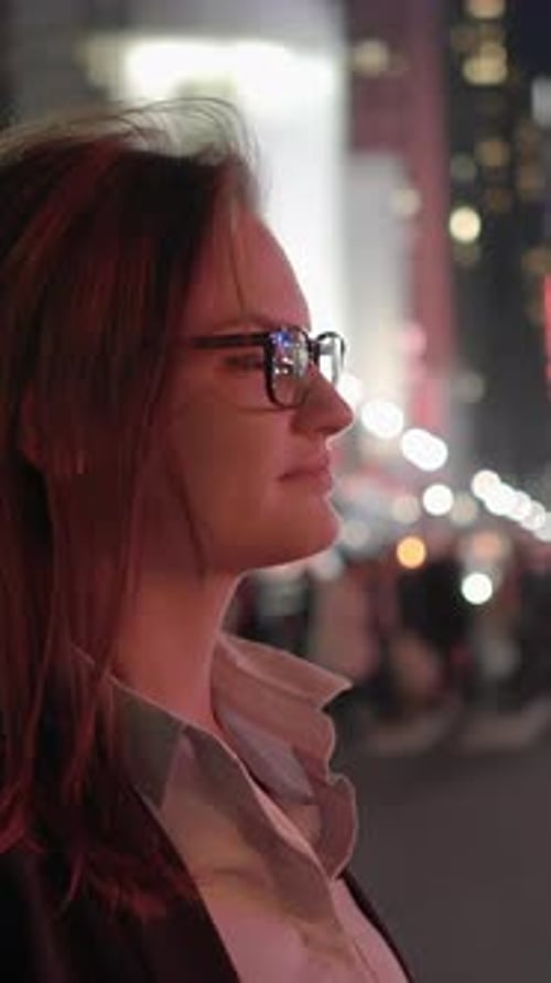 Woman in Glasses Observes City at Night