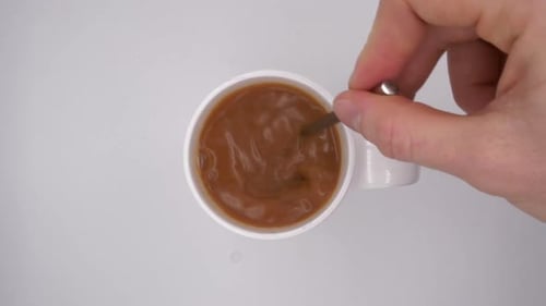 Hand Stirring Coffee in Mug with Spoon