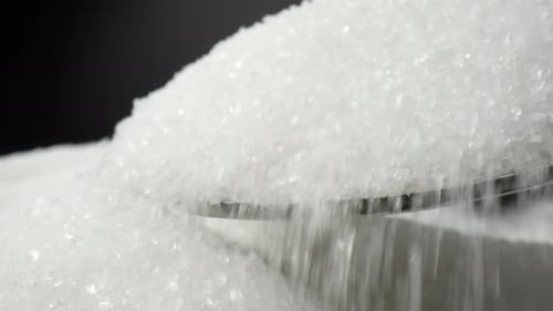 White sugar delicately tumbles off a spoon