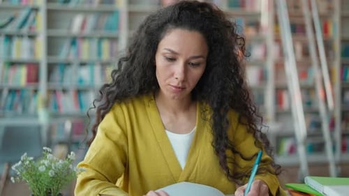 Focused Indian Hispanic Woman Writing Notes Pen in Library Studying Female Girl Student Learning