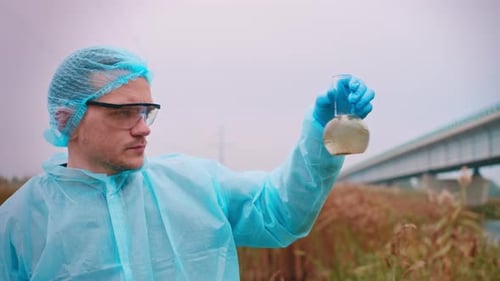 Scientist Examines Murky Water Sample by Wheat Field