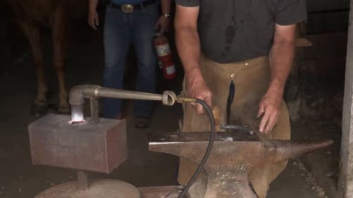 Blacksmith Shaping Horseshoe on Anvil in Workshop