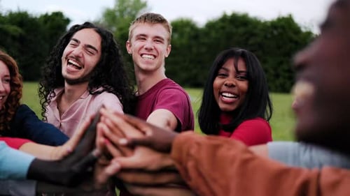 Team of people stacking hands in circle in summer day. Group of friends celebrating together at park