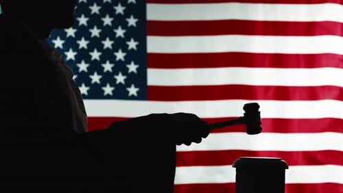 Silhouette of Judge Striking Gavel Against American Flag