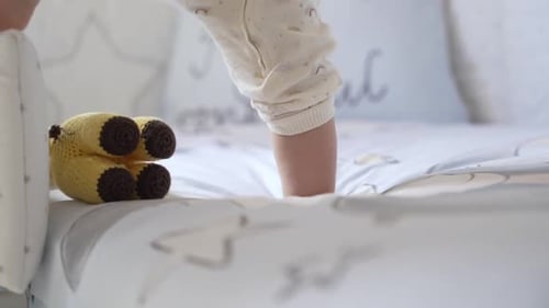 Infant Walking on Bed Next to Stuffed Animal