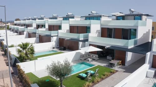 Pristine White Residential Villas Featuring Private Turquoise Pools Manicured Green Lawns and Sleek