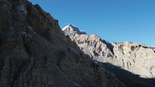 Flying over mountain ridgeline, steep rocky mountain ranges and blue sky in Nepal