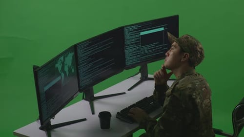 Side View Of Man Soldier Thinking While Write Code With Multiple Computer Screens In Green Screen